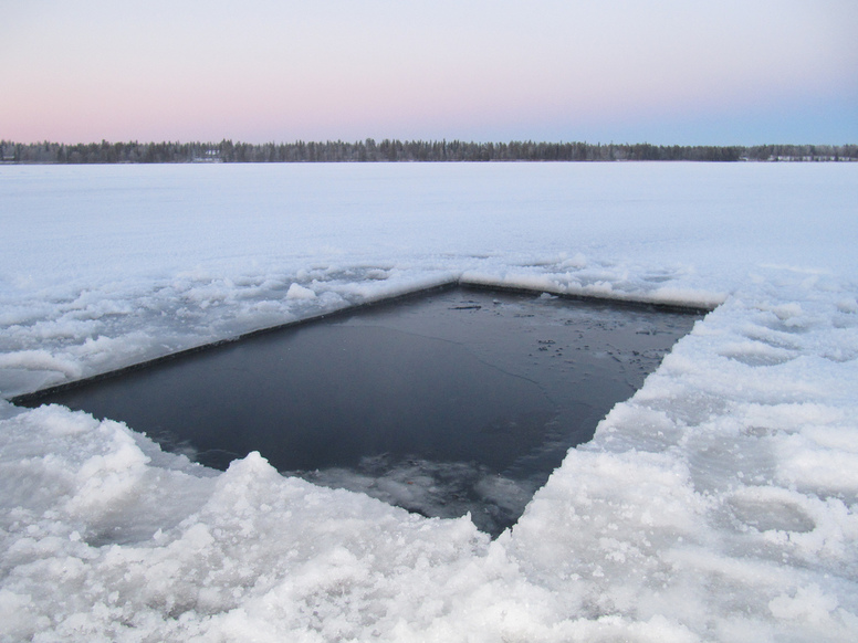 Díra vysekaná v zamrzlém jezeře pro schlazení po sauně